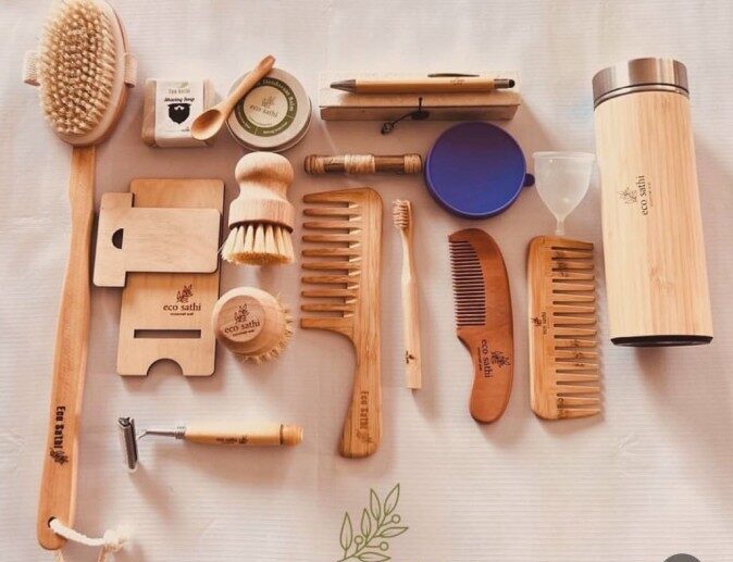 Flat lay of Eco Sathi bamboo products — brushes, combs, razors, thermal bottle and menstrual cup